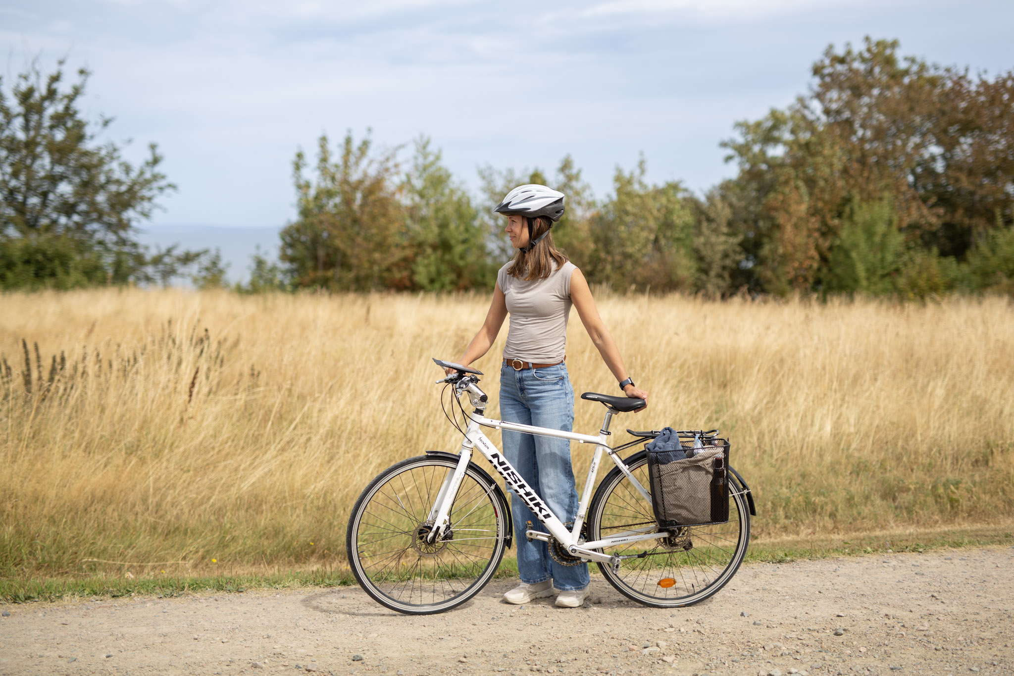 Person with a bike on a gravel road with an open field in the background